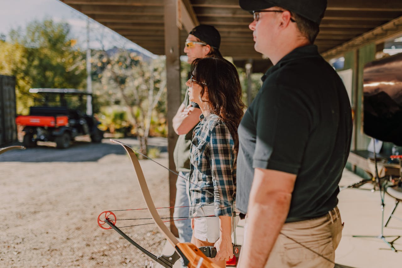 A group of adults practicing archery at an outdoor range, focusing on technique.